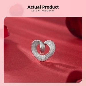 Macro detail of a 925 sterling silver heart charm with a brushed texture on red velvet