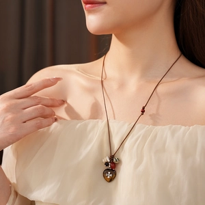 Detail of bohemian wax cord necklace with heart-shaped stone pendant and colorful wooden beads
