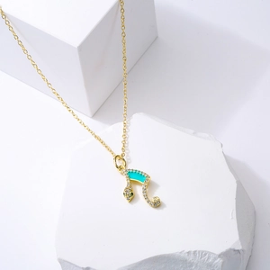 Gold-plated snake pendant necklace with turquoise enamel and crystals on white blocks