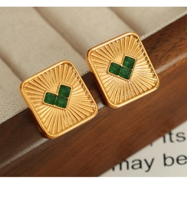 Macro view of gold square stud earrings with green heart-shaped gemstone pattern