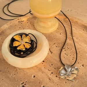 Detailed close-up of 18k gold and silver flower pendants with textured metal finish