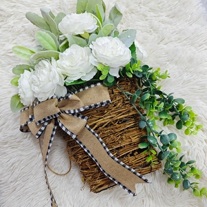 Close-up of white peony wreath with eucalyptus leaves and burlap bow on vine basket