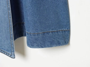 Detailaufnahme von blauem Denim-Stoff mit hochwertigen orangefarbenen Kontrastnähten