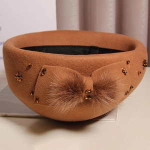 Detail of wool beret featuring a plush fur bow and amber beads in vintage style