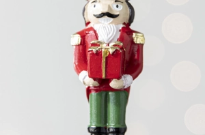 Close-up of resin Nutcracker ornament with red uniform and gold gift box detail