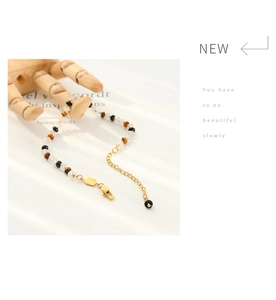 Détail d'un bracelet en perles avec œil de tigre, perles blanches et fermoir doré