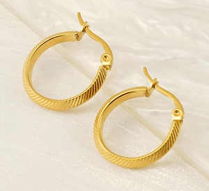 Detail of gold 18K stainless steel hoop earrings featuring textured diagonal stripes