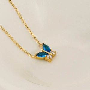 Détail d'un collier pendentif papillon avec pierres bleues et chaîne dorée