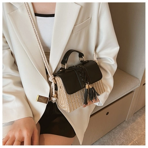 Detail of straw woven crossbody bag with black leather flap and stylish tassel accents