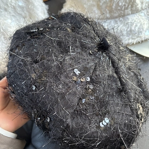 Détail du béret noir à paillettes avec texture brossée et finitions scintillantes