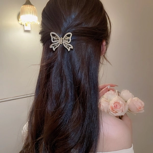 Detail of elegant gold hollow butterfly hair claw clip worn on long brunette hair