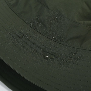 Close-up of water droplets on the waterproof dark green fabric of the bucket hat
