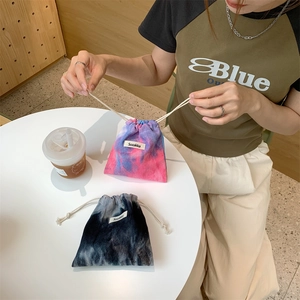 Close-up of tie-dye corduroy drawstring bags with brand label on a cafe table