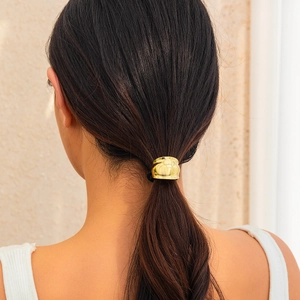 Close-up of a minimalist polished gold metal hair cuff for elegant ponytail styling