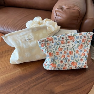 Close-up of textured bubble fabric and floral print small cosmetic bags on a wooden desk