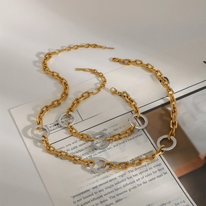 Modern gold and silver mixed chain link necklace displayed on a vintage newspaper background