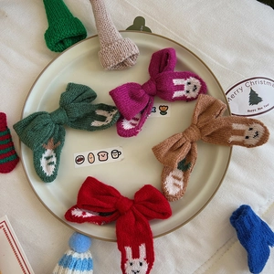 Detail of Christmas knitted bow hair clips with cute rabbit embroidery in festive colors