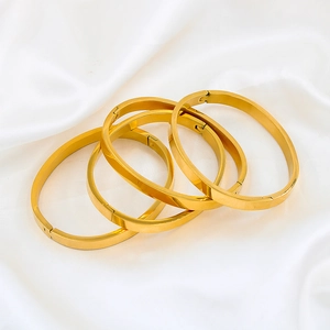 Set of four minimalist 18k gold plated oval bangle bracelets on white satin cloth