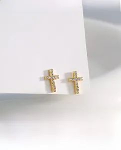 Macro shot of gold cross stud earrings featuring pavé set white zircon stones
