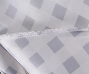Close-up of white and gray plaid fabric texture with detailed stitching line on dress