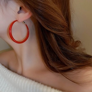 Macro shot of red enamel hoop earrings styled on a model for a vintage look