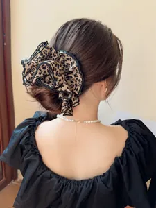 Dettaglio di un grande elastico scrunchie leopardato con volant sui capelli