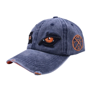 Close-up of distressed denim baseball cap featuring vibrant eye embroidery and side patch