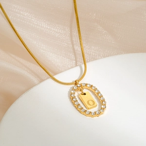 Macro view of gold stainless steel necklace with sparkling crystal oval and letter O
