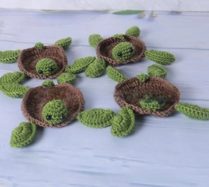 Detailed view of hand-crocheted turtle coasters with spiral shell patterns on wood