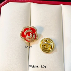 Detailed close-up of a red rose brooch with white crystals and gold clutch back