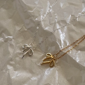Minimalist 925 silver bow pendant necklace shown in gold and silver finishes on white paper