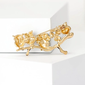 Golden owl branch brooch back view showing secure pin fastening on white pedestal
