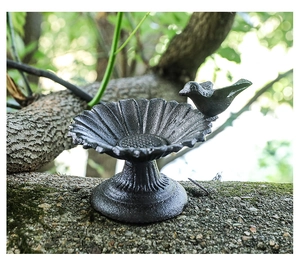 Close-up of cast iron sunflower bird feeder with vintage texture and bird figurine