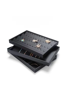 Macro detail of black PU leather jewelry trays showing velvet ring slots and organizers