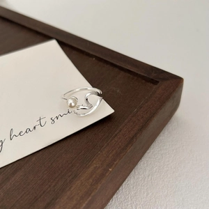 Macro shot of silver pearl ring with wavy design resting on a wooden display tray
