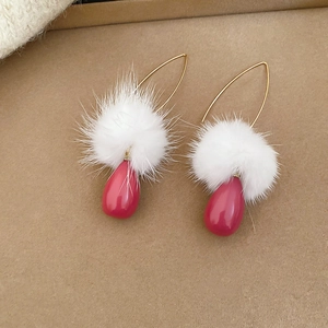 Dettaglio di orecchini con pompon bianchi e pendenti a goccia color magenta