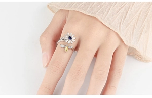 Detailed close-up of a silver sunflower and bee spinner ring with blue gemstones
