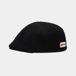 Detail of a vintage black wool beret featuring a stylish white JISIZAN.LING side woven label