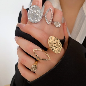 Detailed view of layered gold and silver rings with hammered texture on a model hand