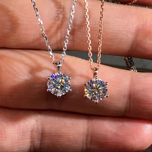 Close-up of silver and rose gold six-prong necklaces with brilliant-cut moissanite stones