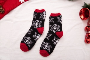 Nahaufnahme von flauschigen Korallenvlies-Weihnachtssocken mit Schneeflocken und Deko
