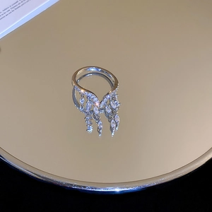 Macro detail of silver V-shaped ring with shimmering zircon tassels on a mirror surface