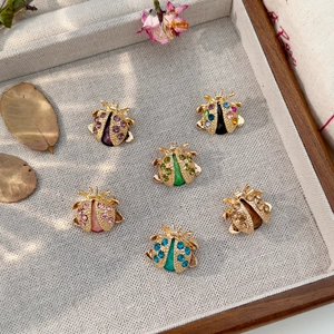 Detailed view of six colorful ladybug brooches with rhinestones on a linen background