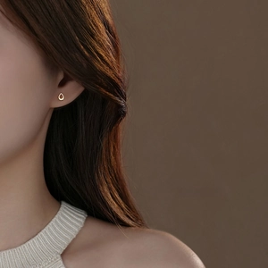 Minimalist S999 sterling silver teardrop earrings in gold finish worn by a model