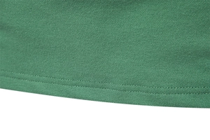 Detail of green piqué cotton polo fabric with precise stitching on the lower hemline