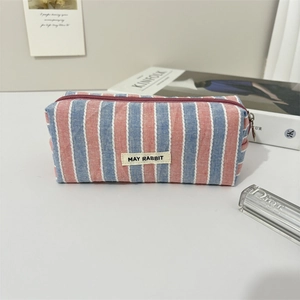Dettaglio della borsa da toilette in tela a righe rosse e blu con cerniera viola