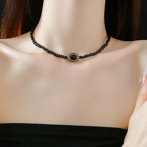 Close-up of vintage black beaded necklace with an oval black gemstone pendant on a model