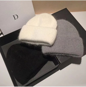 Detailed texture of white, gray and black rabbit fur knit beanies for autumn winter