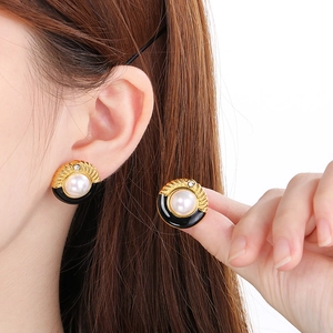 French palace style stainless steel pearl earrings worn by a model on white background