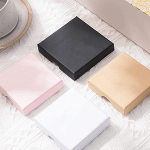 Square drawer gift boxes in pink black white and kraft colors on white textile